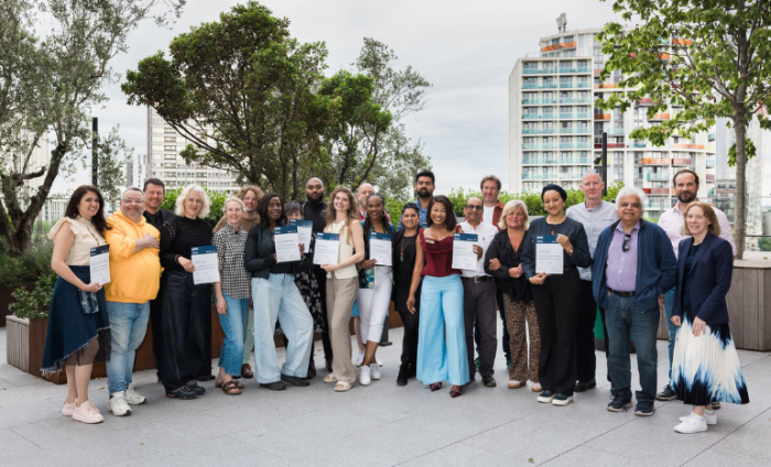 Participants of the Business Builder programme standing in a line holding their certificates of completion.